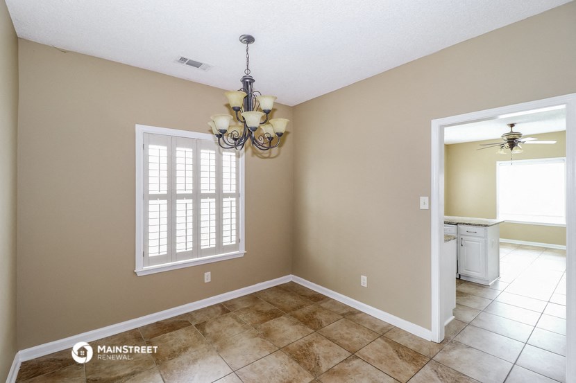 an empty dining room with a chandelier and a window