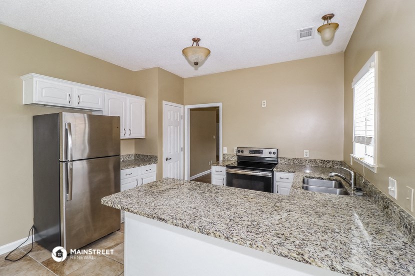 a kitchen with granite counter tops and a stainless steel refrigerator