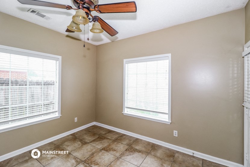 the living room of a home with a ceiling fan and two windows