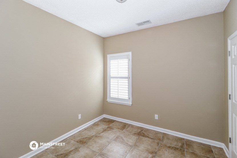 the spacious living room with a window and tiled floors