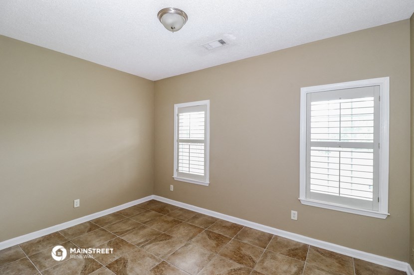 the spacious living room with two windows and a tiled floor