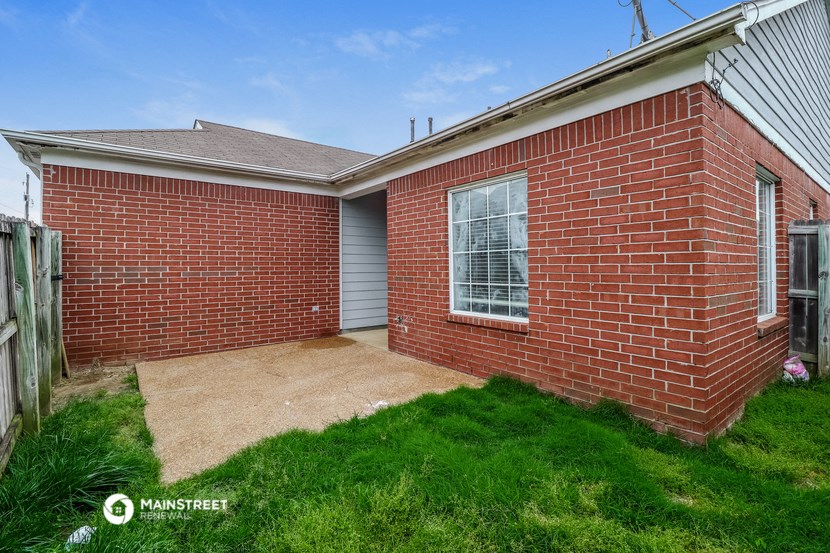 the outside of a brick house with a driveway and grass