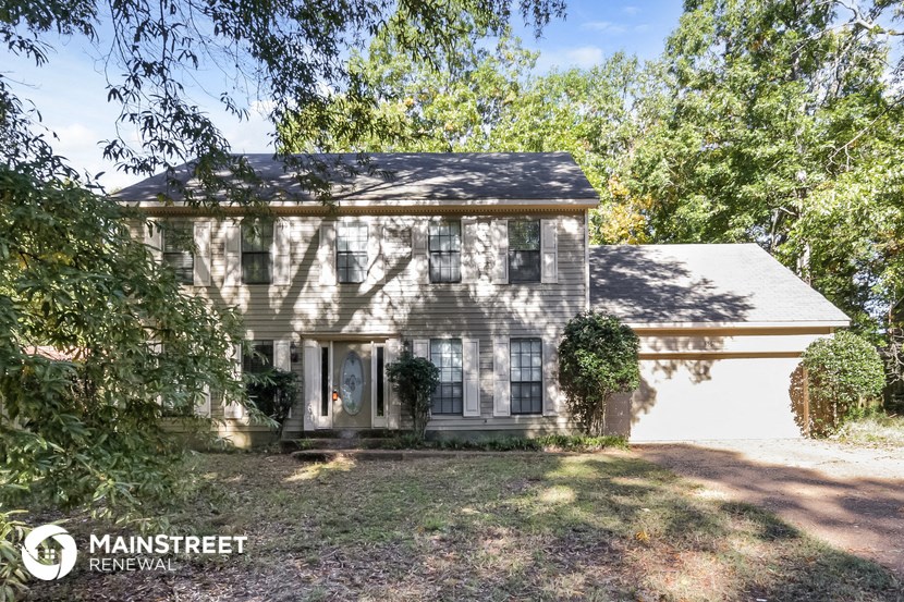 a white house with black shutters and trees