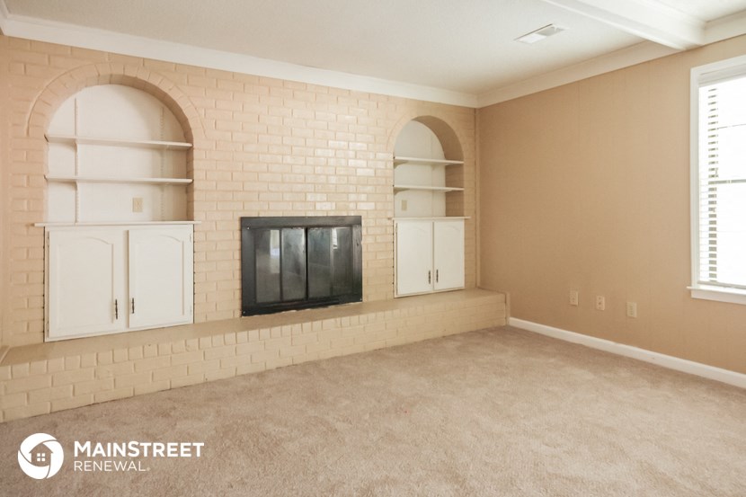 a living room with a brick fireplace and white shelves
