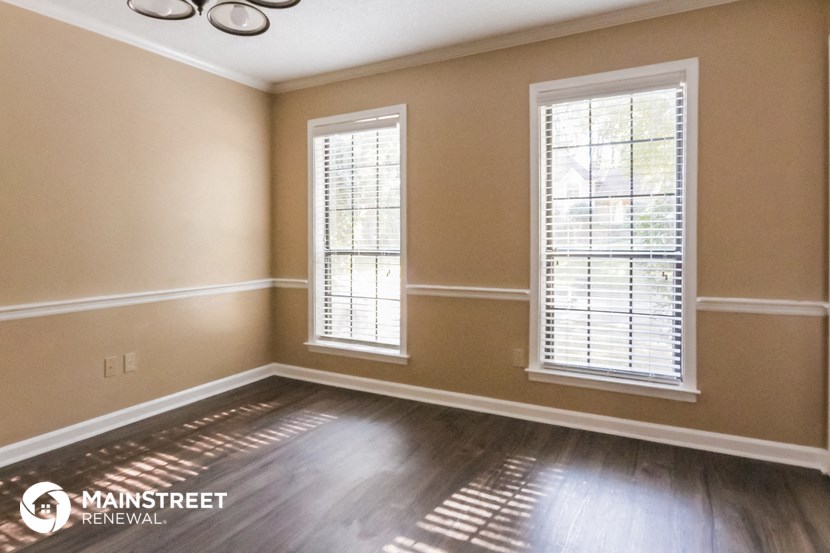 a living room with a hard wood floor and two windows