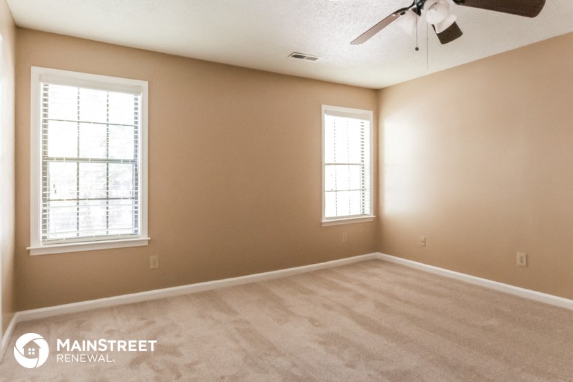 a bedroom with a ceiling fan and two windows