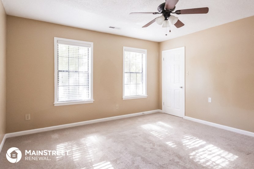 a empty room with a ceiling fan and two windows