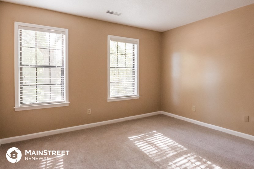 a bedroom with two windows and a carpeted floor