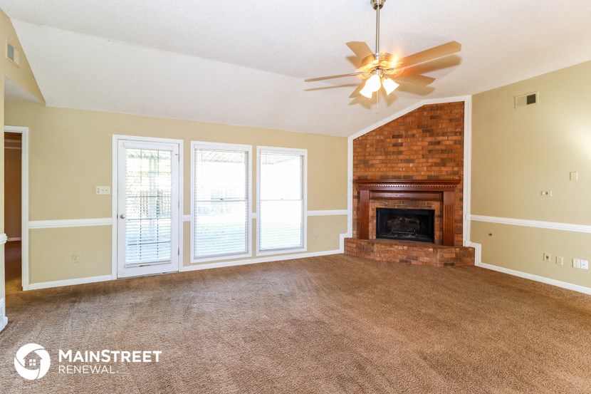 an empty living room with a fireplace and a ceiling fan
