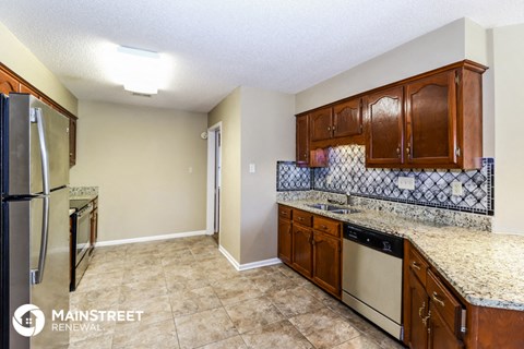 a kitchen with granite counter tops and wooden cabinets and a stainless steel refrigerator