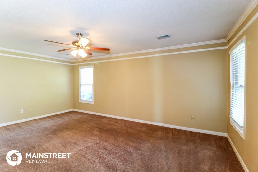 an empty living room with a ceiling fan and a window