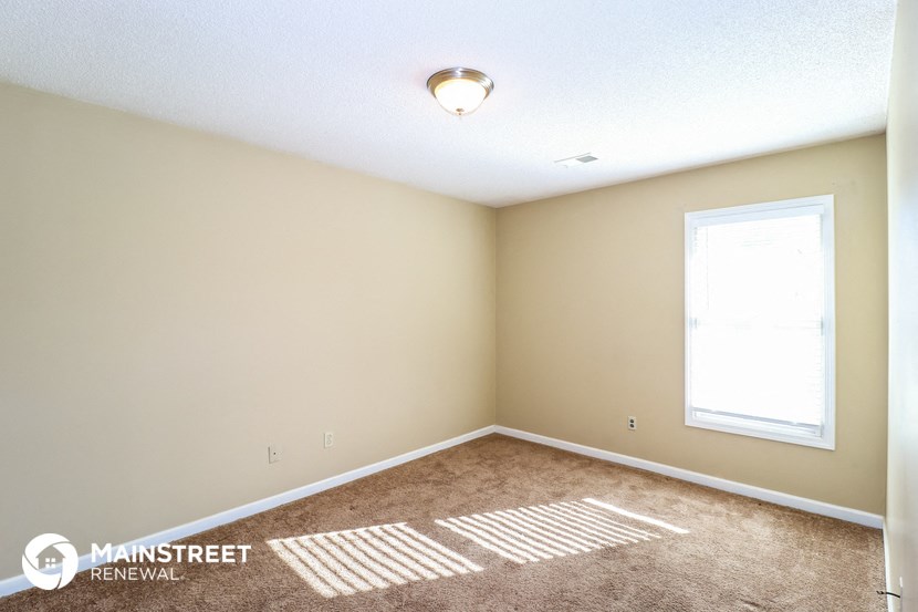 the upstairs bedroom with carpeted flooring and a window