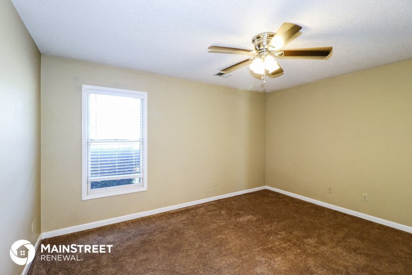 an empty room with a ceiling fan and a window
