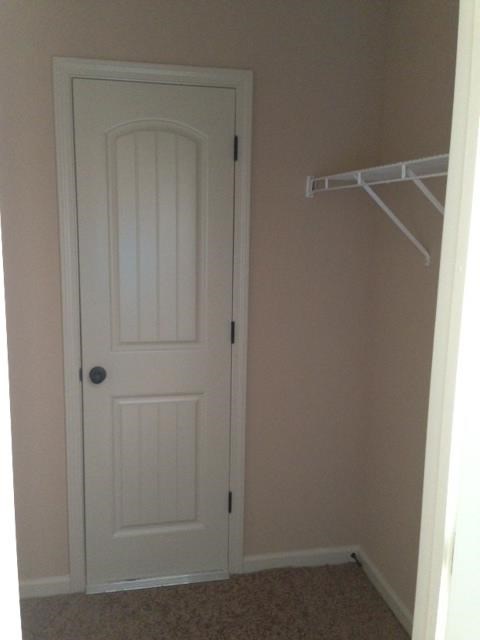 a closet with a white door and a white closet hanger