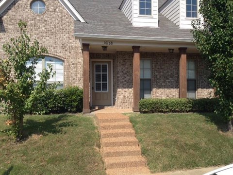 a brick house with a sidewalk in front of it