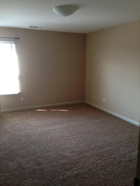 an empty room with a window and a carpeted floor