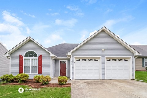 a blue house with a red door and a driveway