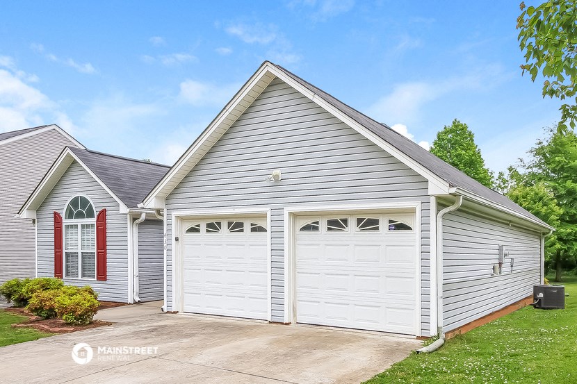 a white garage with two white doors on the side of a house