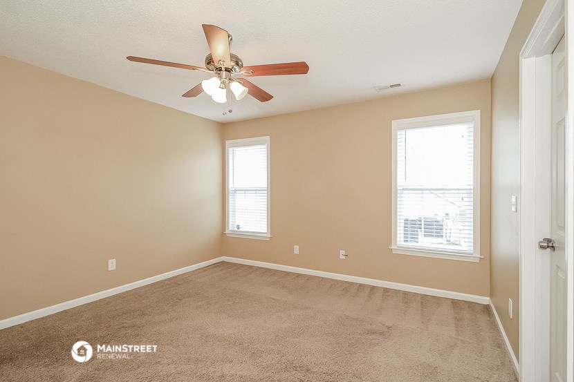 an empty room with a ceiling fan and two windows