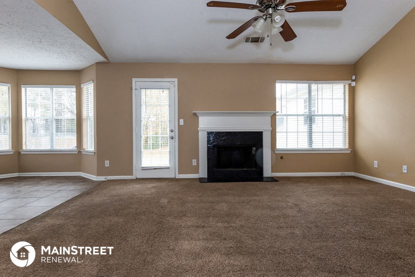 an empty living room with a fireplace and a ceiling fan