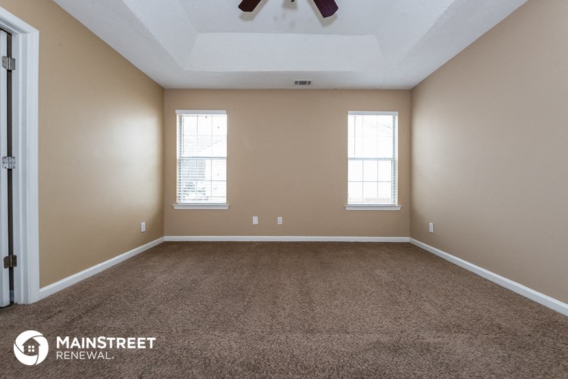 an empty room with carpet and a ceiling fan