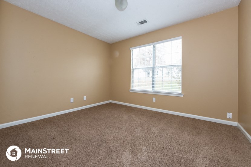 the spacious living room with carpeting and a large window