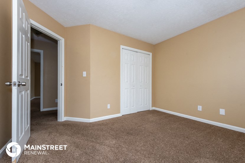 the living room of an apartment with carpet and a door