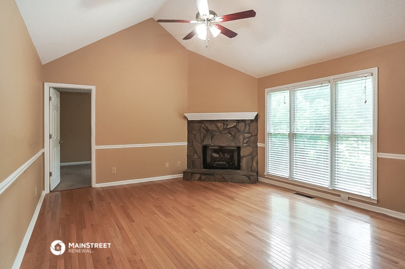 an empty living room with a fireplace and a ceiling fan
