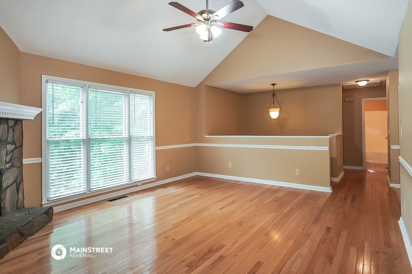 an empty living room with wood floors and a ceiling fan