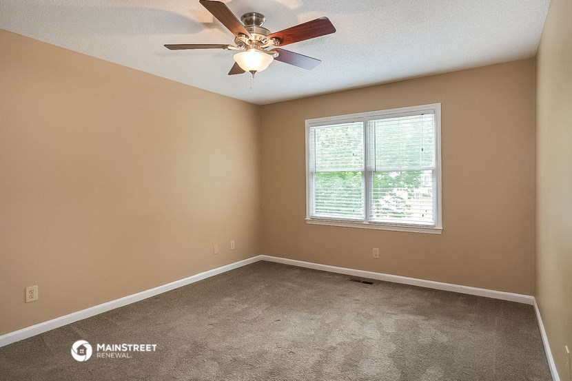 an empty room with a ceiling fan and a window