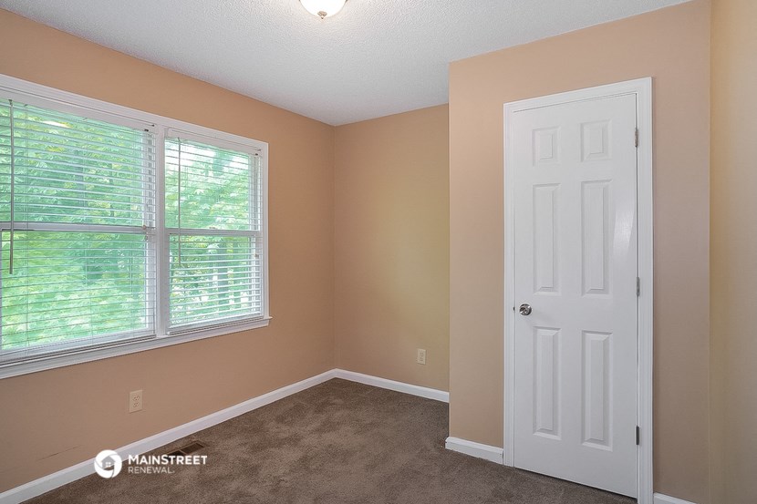 the bedroom of a house with a white door and window