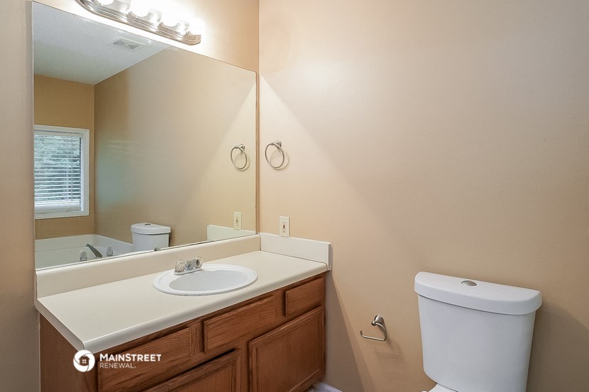 the bathroom has a large mirror and a sink and a toilet