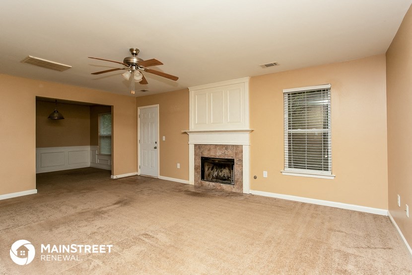 a living room with a fireplace and a ceiling fan