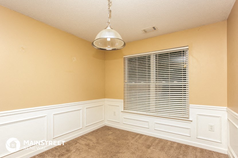 a dining room with white walls and a window