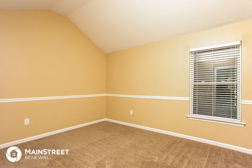 the bedroom of a house with a window and a carpeted floor