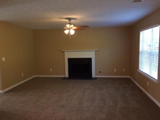 an empty living room with a fireplace and a ceiling fan
