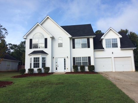 a white house with black shutters and a lawn