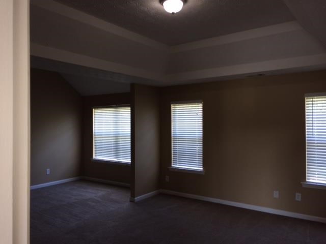 an empty living room with three windows