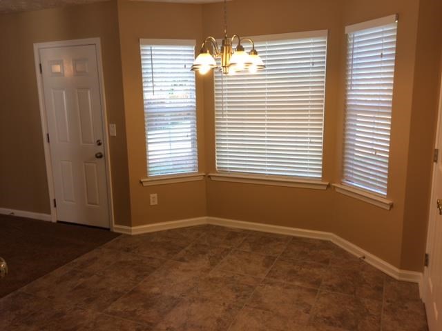 a dining room with three windows and a door