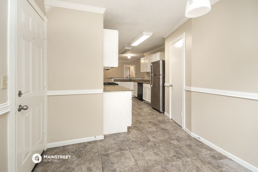 a renovated kitchen with white cabinets and a long hallway with a refrigerator and a sink