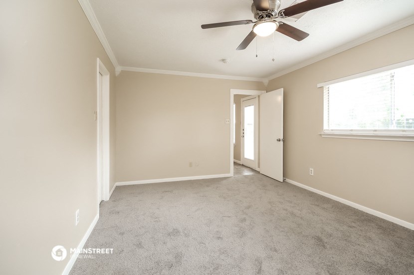 an empty living room with a ceiling fan