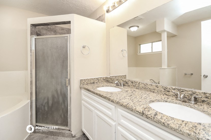 a bathroom with two sinks and a shower and a mirror