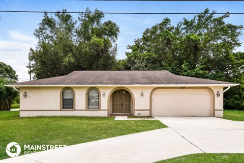 the front of a white house with a driveway and grass