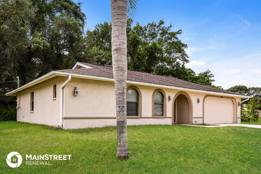 a beige house with a palm tree in the yard