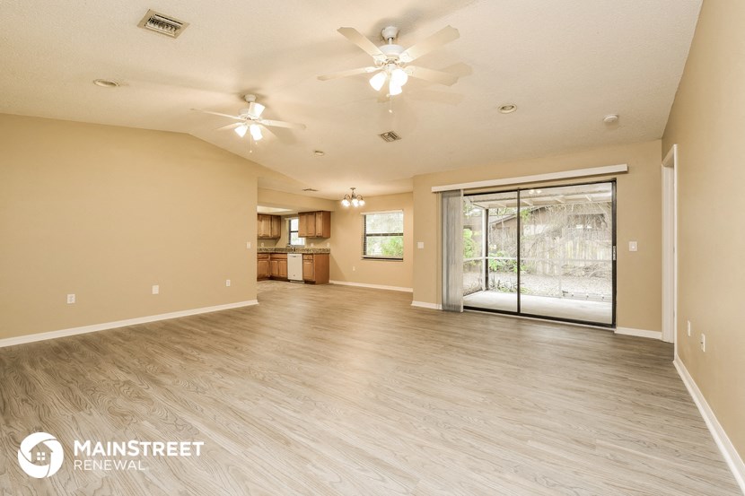 a spacious living room with a kitchen and a ceiling fan