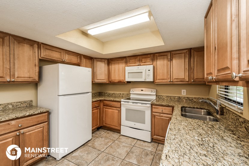 a kitchen with wood cabinets and white appliances and granite counter tops
