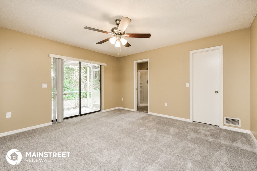 an empty living room with a ceiling fan and a sliding glass door
