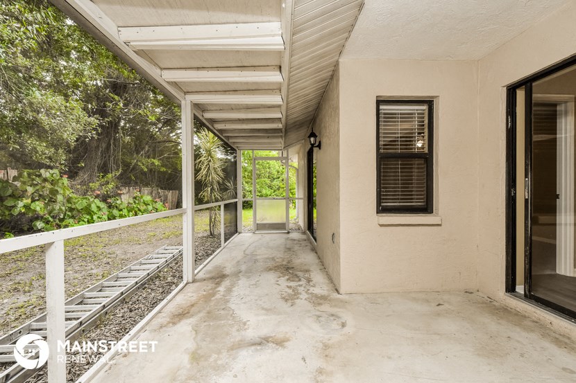 a covered porch with a view of the yard and the woods