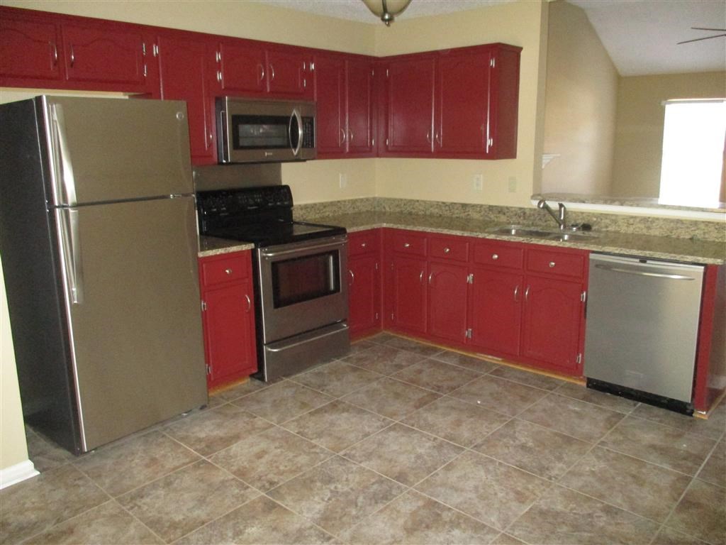 a kitchen with red cabinets and stainless steel appliances