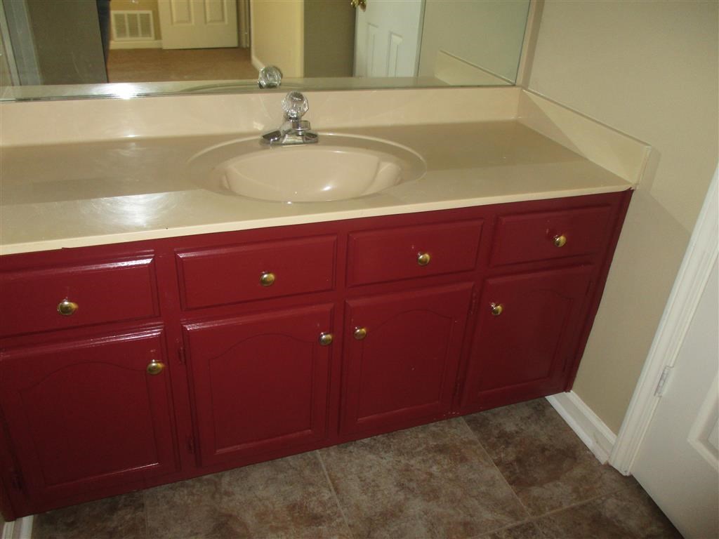 a bathroom vanity with red cabinets and a sink